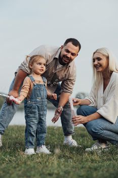 Portrait of Happy Young Family, Mom and Dad with Their Little Daughter Having Fun Outdoors Outside City