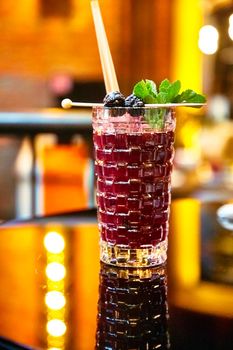 Lemonade of red berries (blueberries, blackberries, black currants, cherries) in a glass is on the table