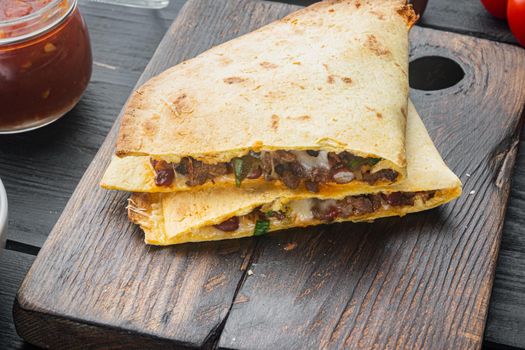 Quesadilla with chicken, cheese and vegetable, on black wooden table background