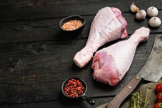 Raw turkey legs ingredients set , with old butcher cleaver knife, on black wooden table background, with copy space for text