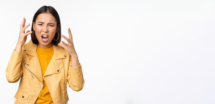 Asian angry woman arguing, shaking hands angry and screaming, shouting with frustrated face, standing over white background.