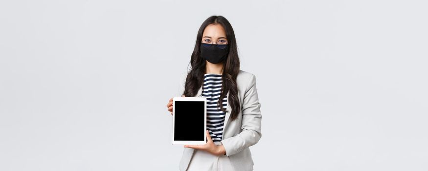 Business, finance and employment, covid-19 preventing virus and social distancing concept. Confident female real estate broker showing deal for client on digital tablet sreen, wear face mask.