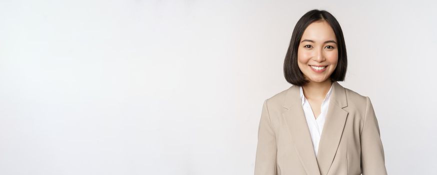 Portrait of successful businesswoman in suit, smiling and looking like professional at camera, white background.