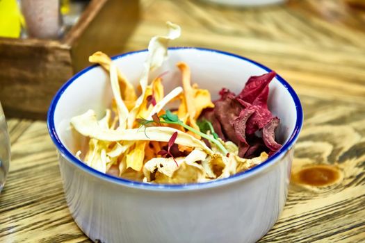 Dry chips from vegetables (carrots, beets, celery, potatoes) lie in a bowl.