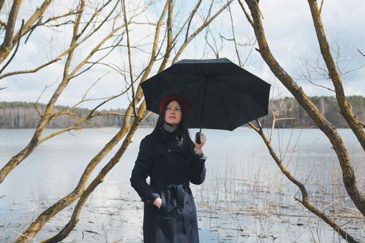 Portrait of a young nice woman with black umbrella on the beach outdoors