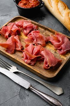 Slices of prosciutto di parma or jamon serrano, on gray stone table background