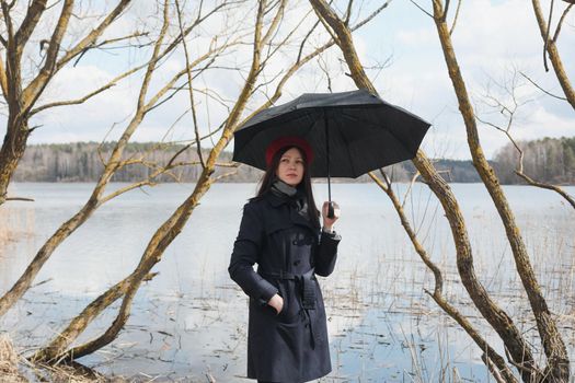 Portrait of a young nice woman with black umbrella on the beach outdoors