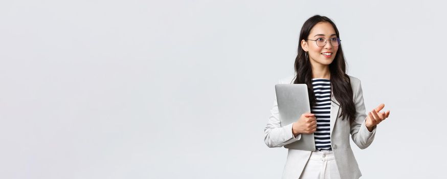 Business, finance and employment, female successful entrepreneurs concept. Smiling professional businesswoman, real estate broker showing clients good deal, carry laptop in hand.