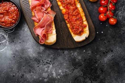 Italian tomato, prosciutto, jamon, ham and cheese bruschetta set, on black dark stone table background, top view flat lay, with copy space for text