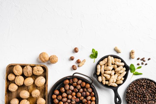 A variety of nuts, peanut, walnut, pine nuts and hazelnut set, on white stone table background, top view flat lay, with copy space for text