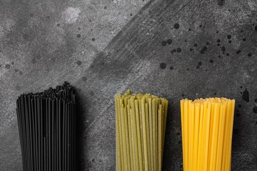 Multi colored spaghetti with ingredients set, on black dark stone table background, top view flat lay, with copy space for text