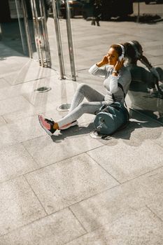 Fitness woman in sportswear resting after morning run in the city. Sports concept