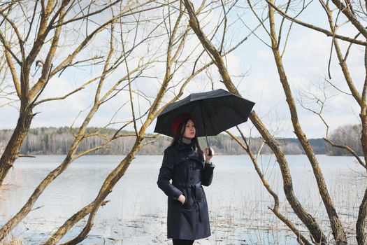 Portrait of a young nice woman with black umbrella on the beach outdoors
