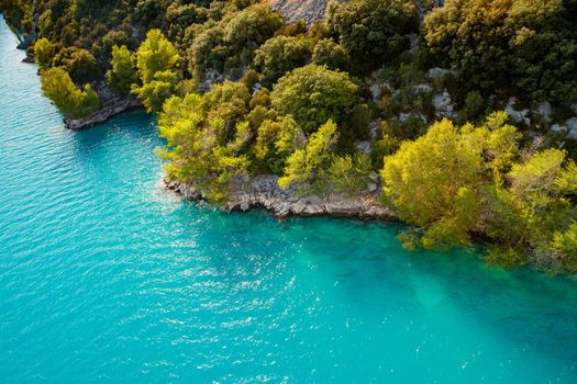 azure water of the lake and slopes of mountains on a background, coast line, green trees, sun light. High quality photo