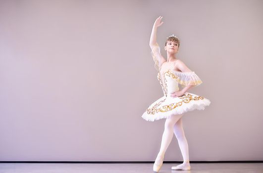 young Classical Ballet dancer in studio is standing on tiptoe.young beautiful graceful caucasian ballerina practice ballet positions in tutu skirt of white swan