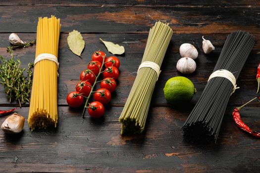 Italian noodles in three colors, black, yellow, green set, on old dark wooden table background