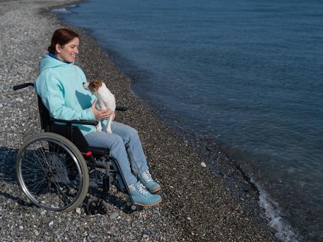 Caucasian woman in a wheelchair with a dog at the sea