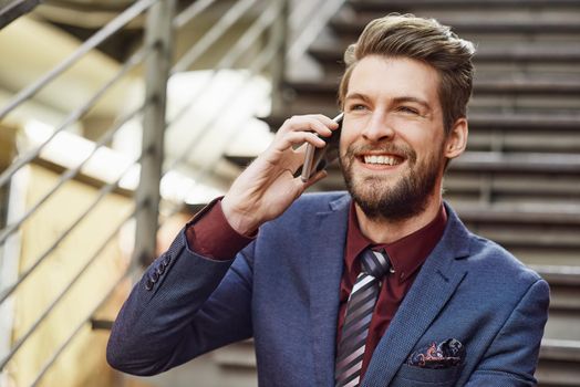 Portrait of a happy young businessman using his phone while out in the city.