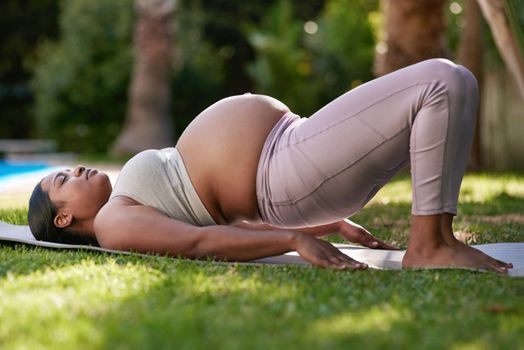 Shot of a pregnant woman doing yoga outside.