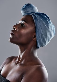 Shot of a beautiful young woman wearing a denim head wrap while posing against a grey background.