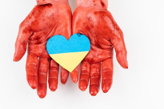 Woman with hands covered in blood holding a heart with the flag of ukraine on a white background