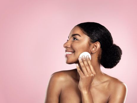 Studio shot of a beautiful young woman cleaning her face with cotton wool.