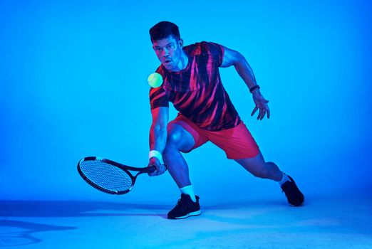 Blue filtered shot of a tennis player in the studio.