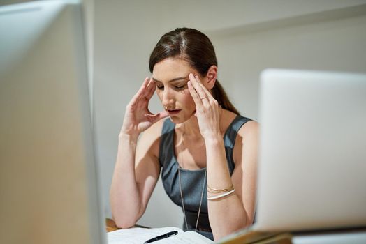 Shot of a businesswoman suffering from a headache at her office desk.