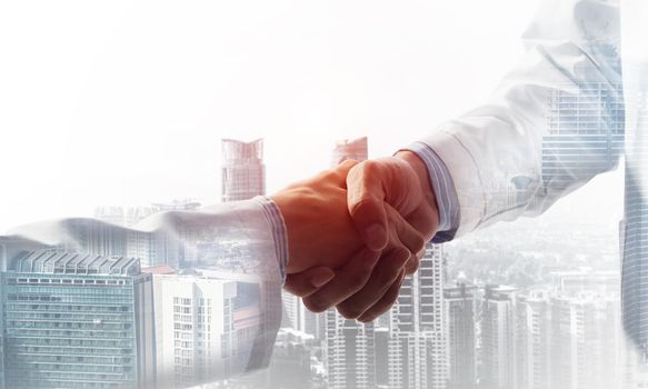 Close-up of the handshake between the two medics. Against the backdrop of the cityscape