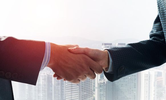 Close-up of the handshake of businessmen. Against the backdrop of the cityscape