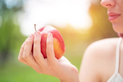 Close-up of the woman's hand with an apple. A young woman is holding an apple.