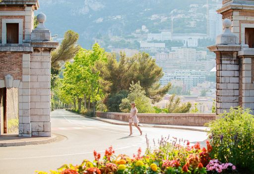 a bright beautiful girl in a light dress and hat walks along the streets of Monaco in sunny weather in the summer, luxury apartments of Monte Carlo on background. High quality photo
