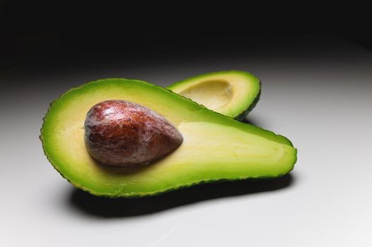 Avocado on old wooden table.Halfs on wooden bowl. Fruits healthy food concept