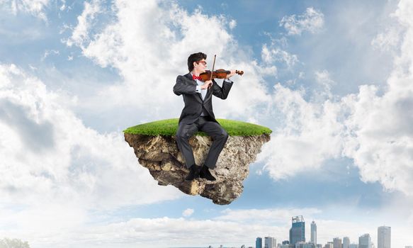 A young businessman plays the violin. Get inspired by business.