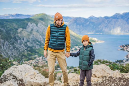 Dad and son travellers enjoys the view of Kotor. Montenegro. Bay of Kotor, Gulf of Kotor, Boka Kotorska and walled old city. Travel with kids to Montenegro concept. Fortifications of Kotor is on UNESCO World Heritage List since 1979.