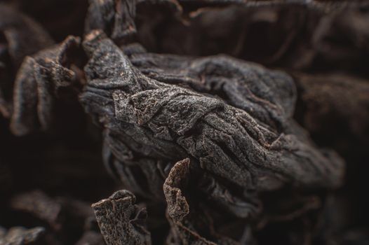 Extreme macro Black loose leaf tea as a background. Texture of dry black tea leaves in shallow depth of field. Dark background. macro mode. black leaf tea closeup.