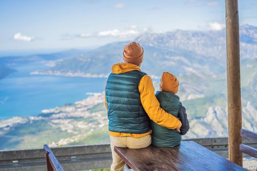 Dad and son travellers enjoys the view of Kotor. Montenegro. Bay of Kotor, Gulf of Kotor, Boka Kotorska and walled old city. Travel with kids to Montenegro concept. Fortifications of Kotor is on UNESCO World Heritage List since 1979.