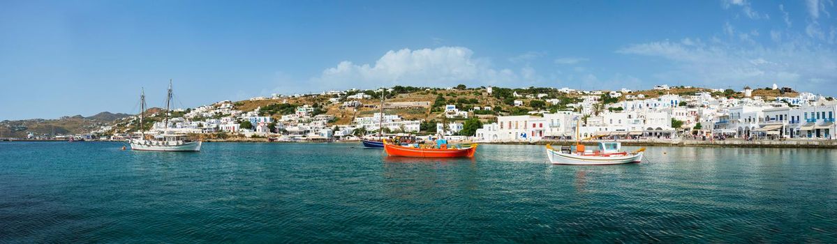 Panorama of greek fishing boats in clear sea water in port of Mykonos. Chora town, Mykonos, Greece