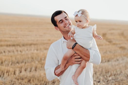 Happy Father Holding His Toddler Daughter in Arms, Happy Father's Day While Standing Outdoors in Field