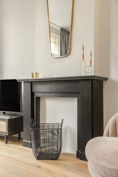 Decorative fireplace in black under the mirror in the living room of a modern house