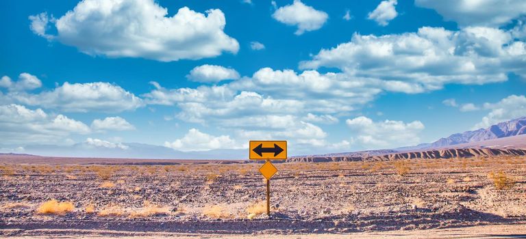 Directional sign in the desert with scenic blue sky and wide horizon. Concept for trip, freedom, holiday and transportation.