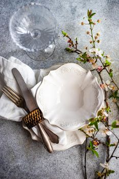 Spring place setting for dinner decorted with fresh blooming cherry flowers