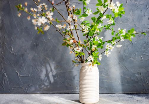 Blooming cherry tree branches in the vase as a spring interior decoration