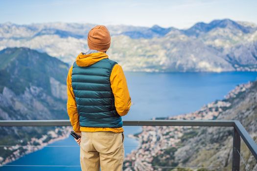 Man tourist enjoys the view of Kotor. Montenegro. Bay of Kotor, Gulf of Kotor, Boka Kotorska and walled old city. Travel to Montenegro concept. Fortifications of Kotor is on UNESCO World Heritage List since 1979.