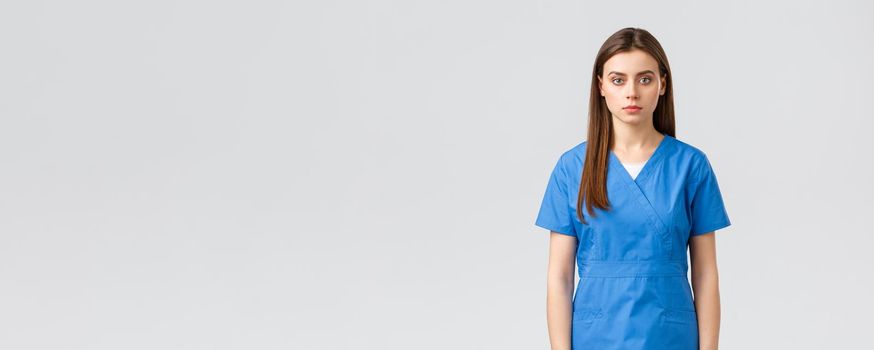 Healthcare workers, prevent virus, insurance and medicine concept. Serious-looking young medical worker, nurse or doctor in blue scrubs, looking determined and confident camera.