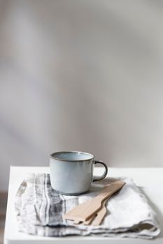 Two white mugs, a kitchen towel, a napkin and wooden frying utensils on the table. Defocus.