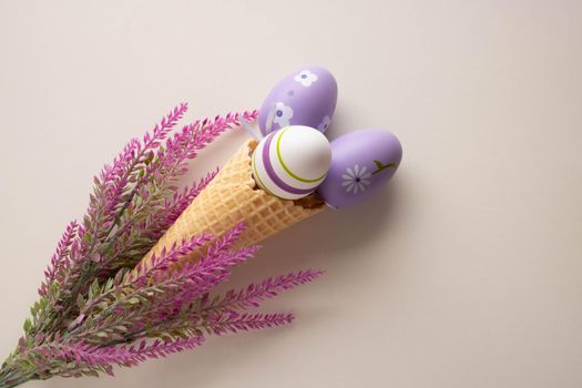 Easter composition, a branch of artificial lavender and three eggs in a waffle cone on a white background.