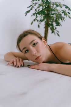 Portrait of young caucasian woman in red cloth laying near flowerpot. Dreamy