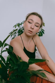 Portrait of young caucasian woman in red cloth sitting near flowerpot. Dreamy