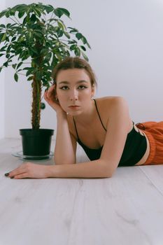 Portrait of young caucasian woman in red cloth laying near flowerpot. Dreamy